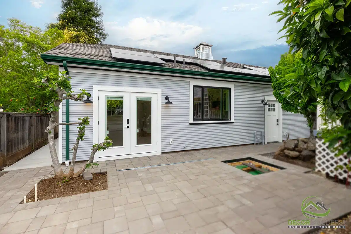 Custom home exterior remodel featuring a white ADU with green roof, concrete patio, and mature landscaping in Morgan Hill, CA