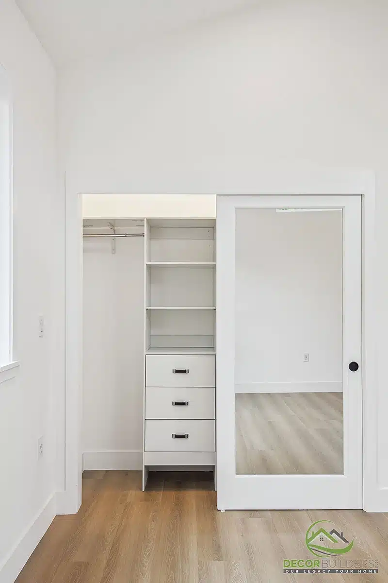 Custom home remodel featuring a white built-in closet organizer with shelving, drawers, hanging storage, and a mirrored sliding door in Morgan Hill, CA