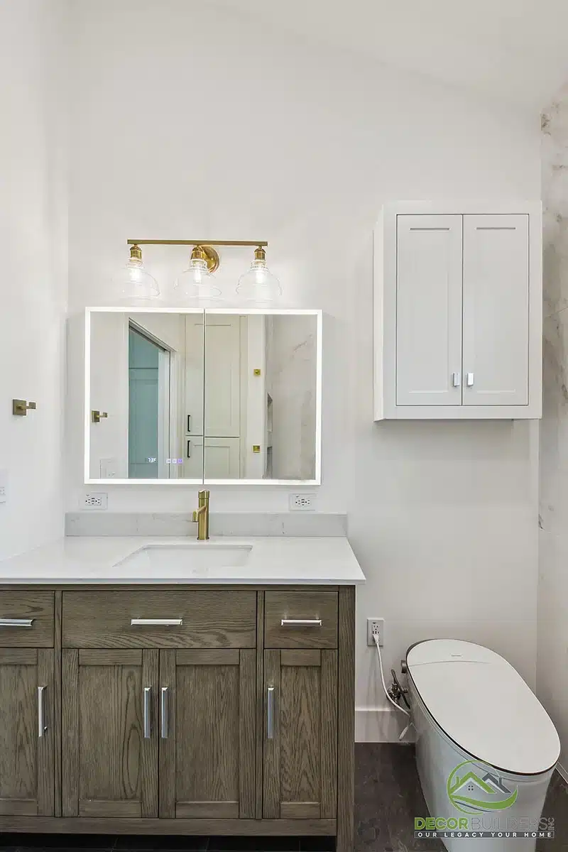Custom bathroom remodel featuring a dark wood vanity, white countertop, white framed mirror, gold fixtures, and white tile walls in Morgan Hill, CA