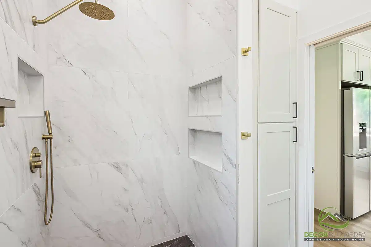 Bathroom remodel showcasing a marble tile walk-in shower with gold fixtures, built-in niche shelving, and glass enclosure in Morgan Hill, CA