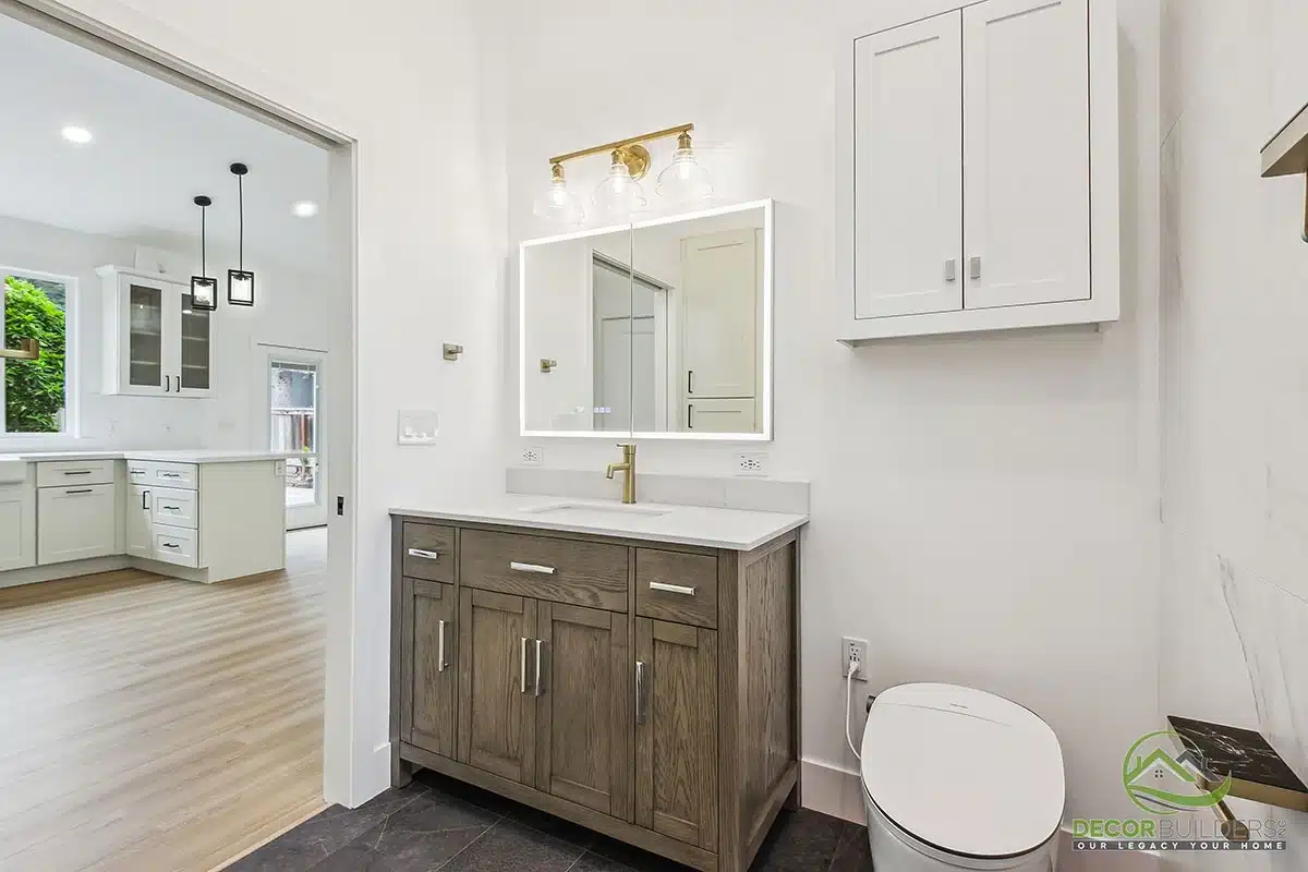 Custom bathroom remodel showcasing a white vanity, marble tile surround, gold fixtures, recessed lighting, and toilet in Morgan Hill, CA