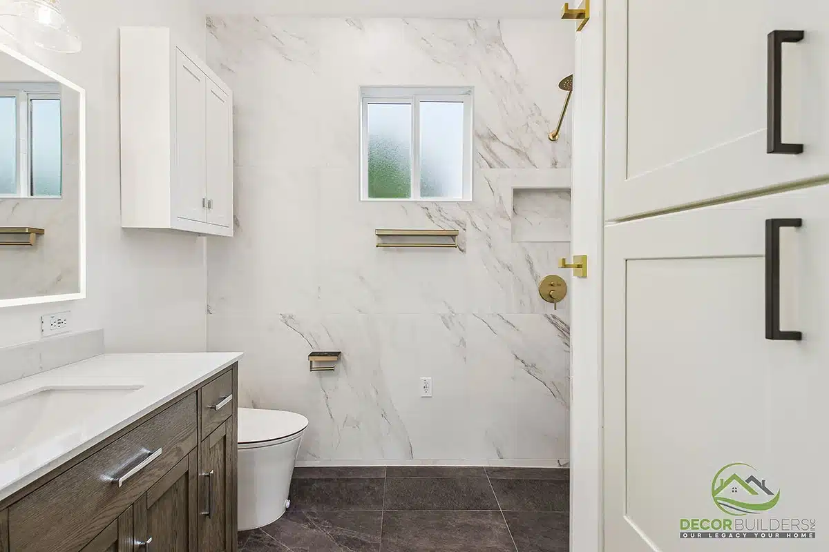 Bathroom renovation featuring a dark wood vanity, marble tile walls, white countertop, gold fixtures, and toilet in Morgan Hill, CA"