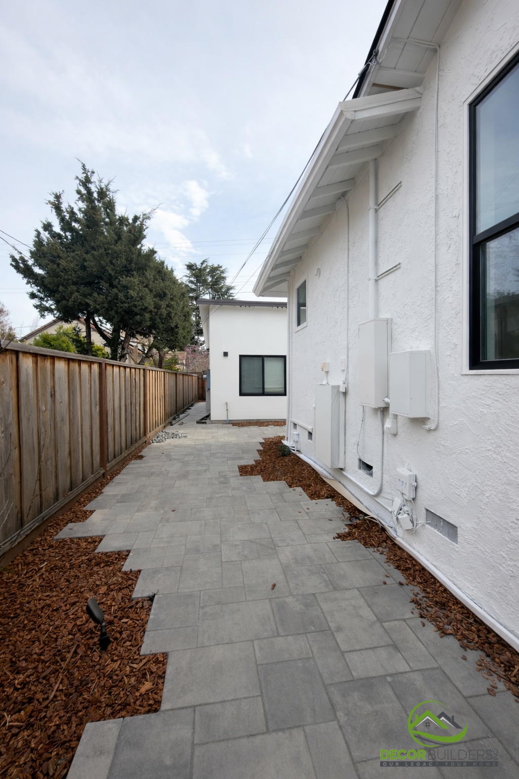 Custom home construction side yard with paver walkway, wood fence, and white stucco exterior, Sunnyvale CA