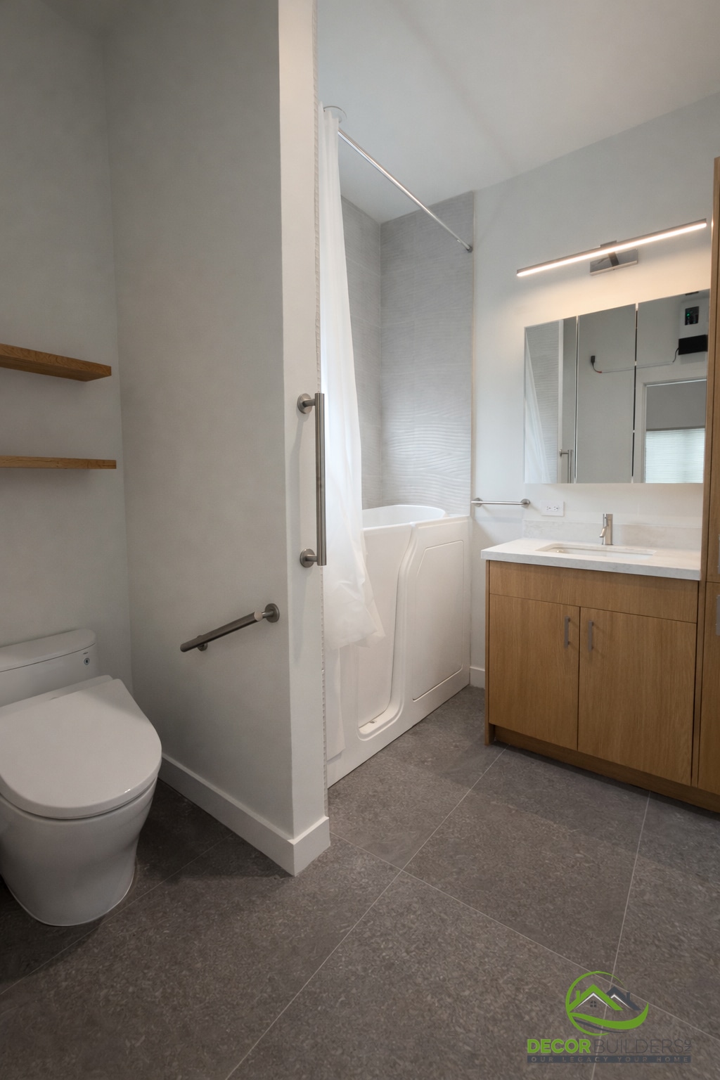 Bath renovation with walk-in soaking tub, grab bars, wood vanity, and gray tile floor in Sunnyvale CA