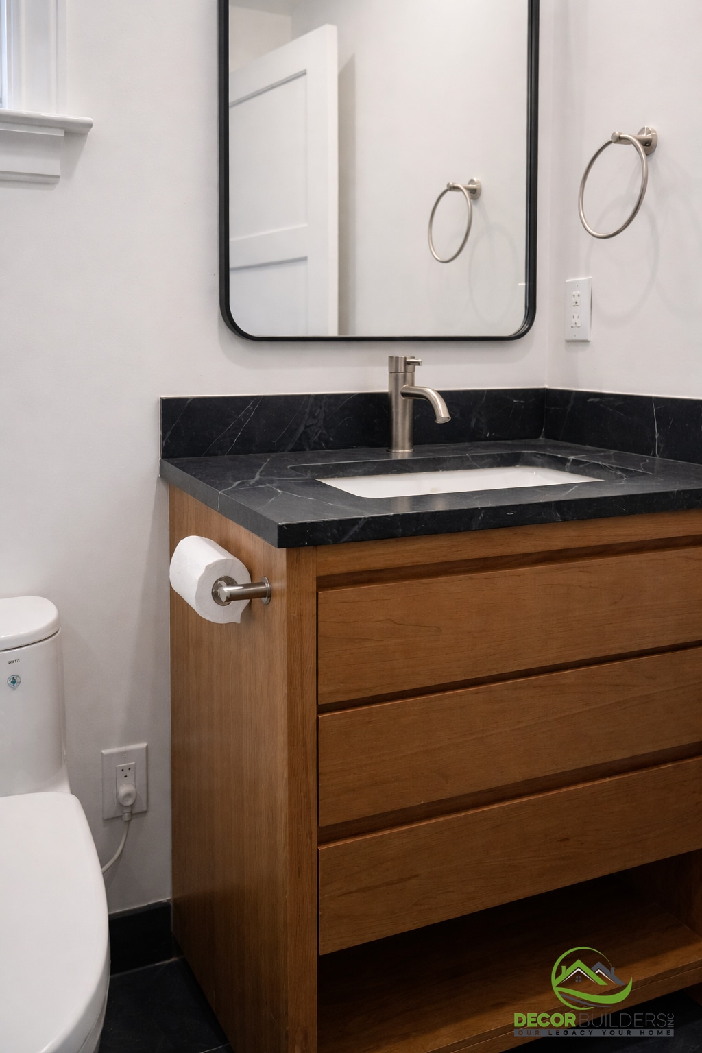 Bathroom renovation featuring a wood vanity with dark granite countertop, undermount sink, and black-framed round mirror in Palo Alto