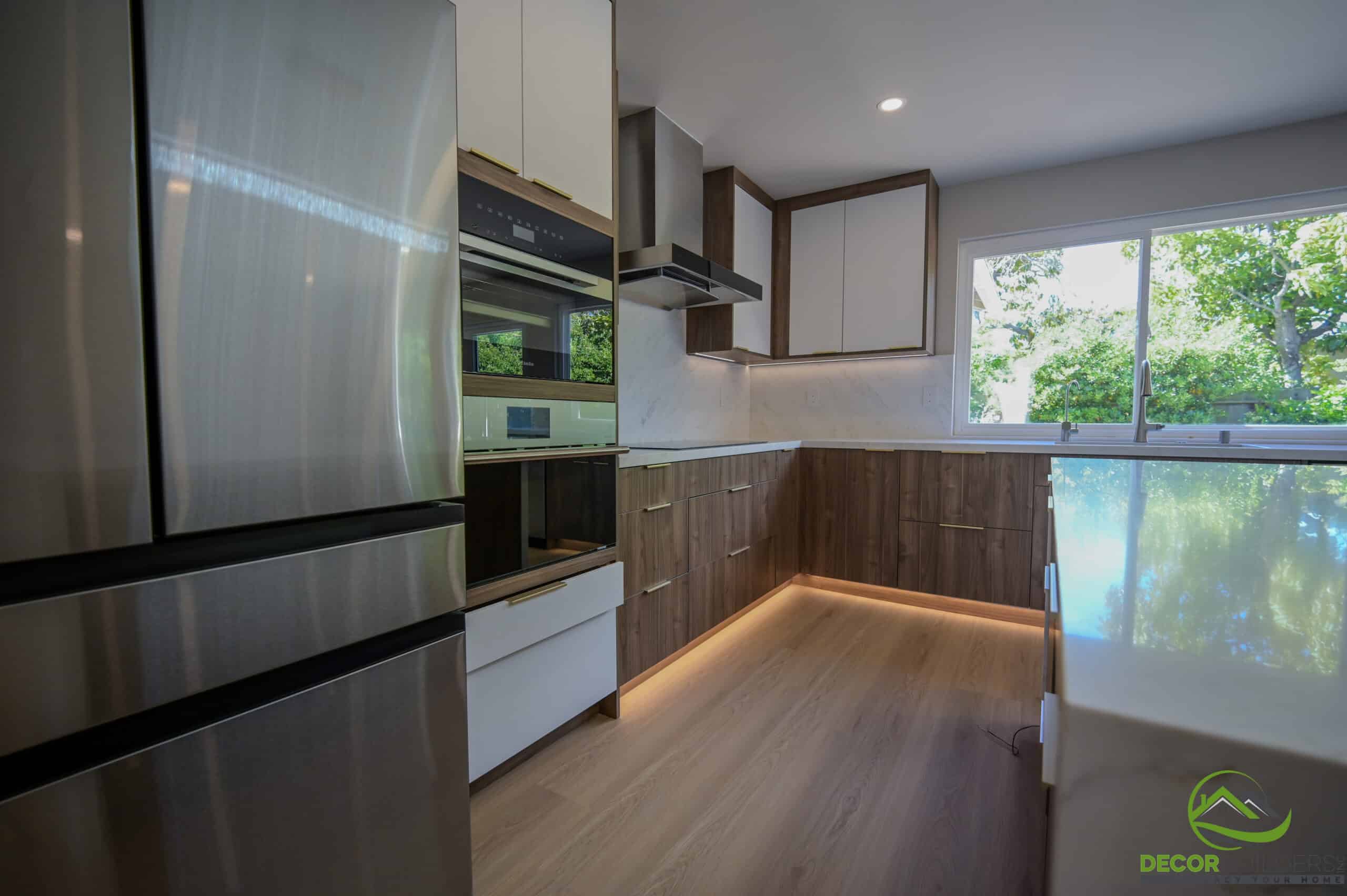 Kitchen renovation with stainless steel refrigerator, built-in oven, wood cabinets, and marble backsplash, Foster City CA