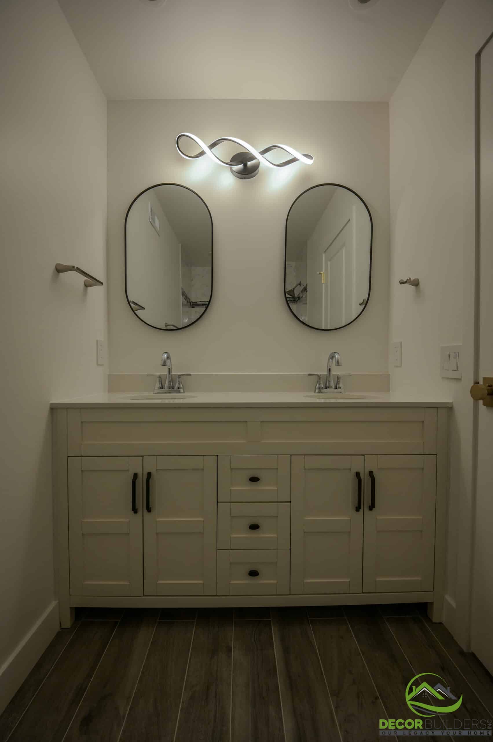 Custom home bathroom double vanity with oval mirrors, sculptural LED light, and white quartz top, Foster City CA