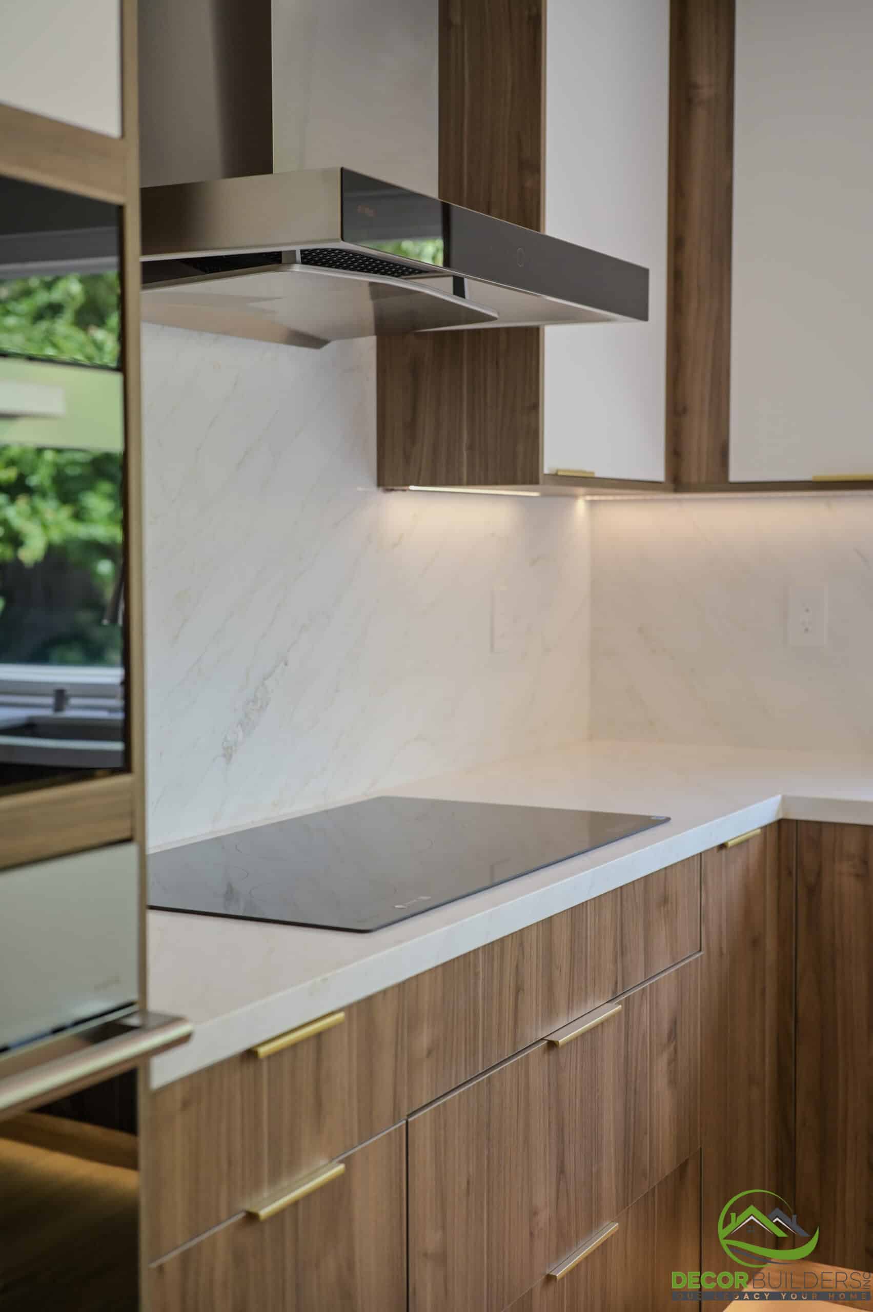 Kitchen remodeling detail with induction cooktop, marble backsplash, range hood, and wood cabinetry, Foster City CA